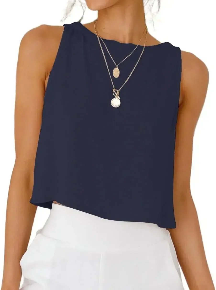 Navy blue sleeveless top with layered gold necklaces, paired with white high-waist pants for modern women's fashion