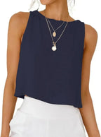 Navy blue sleeveless top with layered gold necklaces, paired with white high-waist pants for modern women's fashion
