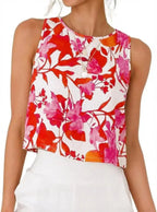 Women's sleeveless floral crop top with vibrant red and pink print, paired with white pants for casual summer style