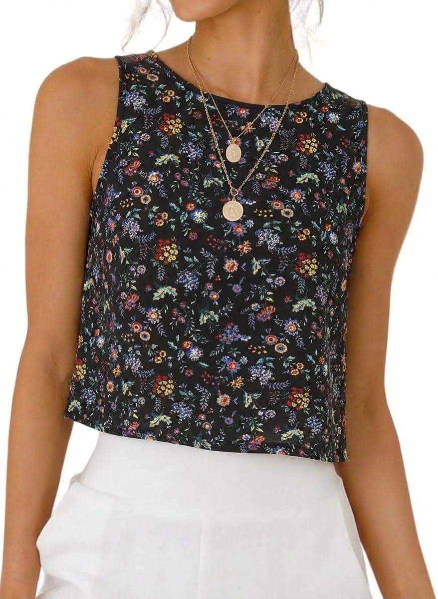 Black floral print sleeveless crop top for women, paired with white pants and layered necklaces.